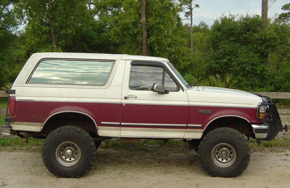 1993 Ford Bronco lifted with large tires, two-tone paint, and brush guard
