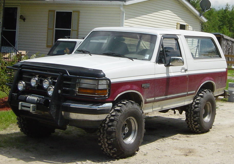 Lifted 1993 Ford Bronco, white and maroon, with brush guard and winch