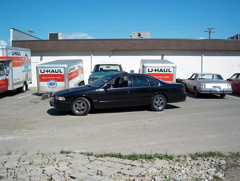 Black 1996 Chevrolet Impala sedan parked next to U-Haul trucks