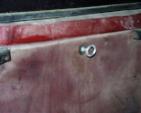 1988 Ford C-350 (Centurion Conversions) - A close-up view of a red interior door panel shows a metal loop fastener attached to the surface.