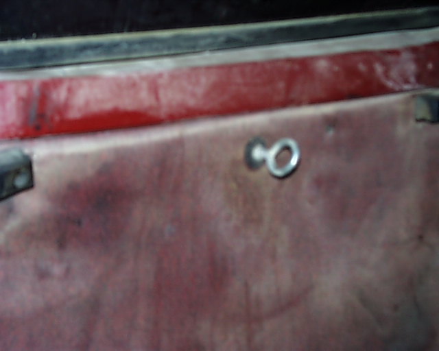 Close-up of a red interior door panel with a metal loop fastener
