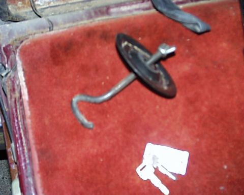 1988 Ford C-350 (Centurion Conversions) - A metal hook and two keys rest on a red carpeted surface, likely inside a vehicle.