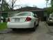 2003 Ford Taurus - Rear view of a white sedan parked in a driveway with a house in the background.