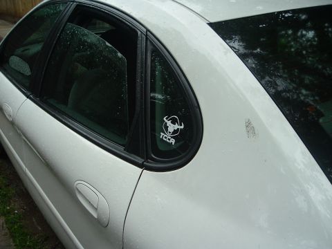2003 Ford Taurus - Side view of a white 2003 Ford Taurus, a TCCA bull sticker on the rear window.