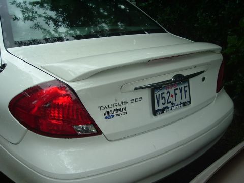 2003 Ford Taurus - The rear of a white Ford Taurus SES sedan is shown, a spoiler and a dealer frame around the license plate.