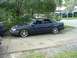 1993 Ford Taurus - A dark blue sedan is parked outdoors, with trees and a building visible in the background.