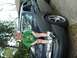 1993 Ford Taurus - A dark sedan is parked outdoors next to a building, with a person visible near the rear wheel.