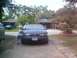 1993 Ford Taurus - A dark sedan is parked in a residential driveway, showing damage to its front end.
