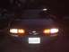 1993 Ford Taurus - A dark sedan is seen from the rear at night, its taillights on.