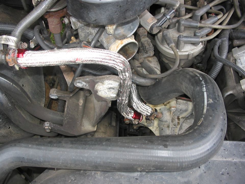 Engine bay detail showing braided coolant line and clamps near the intake