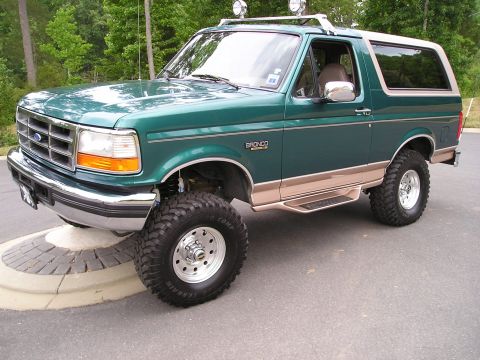 1996 Ford Bronco - This lifted 1996 Ford Bronco features a two-tone paint scheme with tan lower body trim and a roof rack with auxiliary lights.