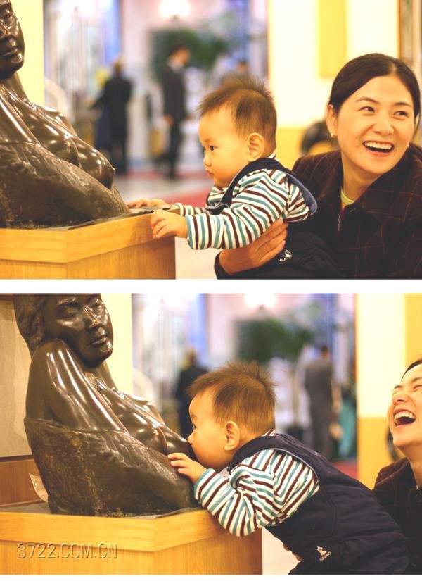Baby reaching for a statue while a woman laughs behind him