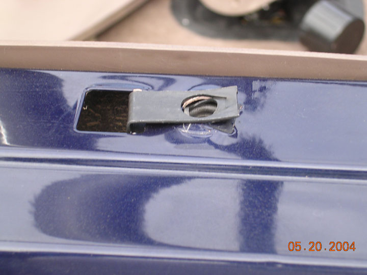 Spring steel U-nut clip installed in a slot on glossy dark blue painted metal panel