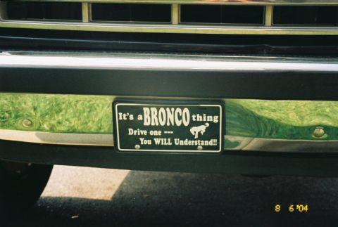 1988 Ford Bronco - A license plate with a Bronco graphic and text is attached to the front bumper of a vehicle.