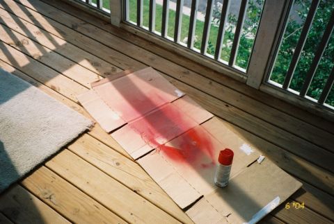 1988 Ford Bronco - Spray paint and tools are laid out on a cardboard sheet on a wooden deck.