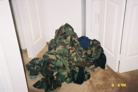 1988 Ford Bronco - Camouflage clothing piled on a carpeted floor near white doors.