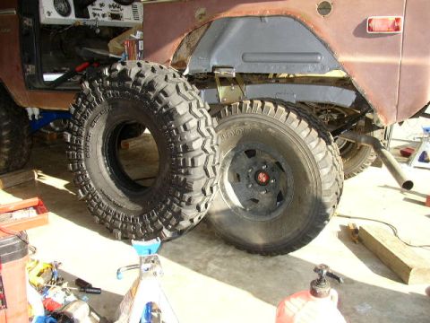 1995 Ford Bronco - Vehicle under repair with large off-road tires and exposed undercarriage visible.