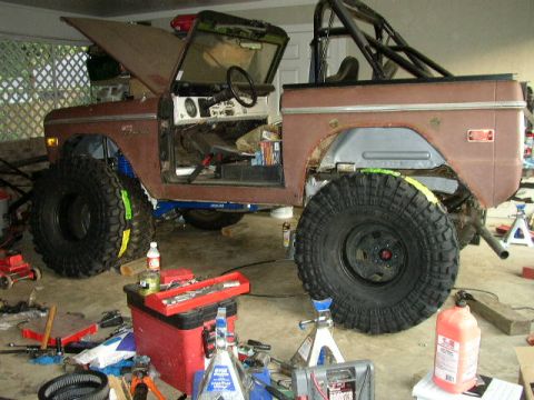 1995 Ford Bronco - This SUV, likely a 1974 model, is in a garage with its hood up and large off-road tires installed.