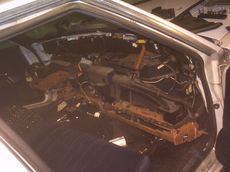 Sedan interior with dashboard removed showing HVAC box, steering column and loose wiring