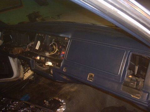 1991 Ford LTD Crown Victoria - Interior shot of a partially disassembled blue dashboard, with the radio and HVAC control bezel removed to expose loose wiring harnesses an…