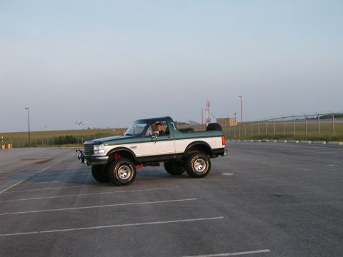 1994 Ford Bronco - Lifted two-tone green and white Ford Bronco parked in an empty lot.