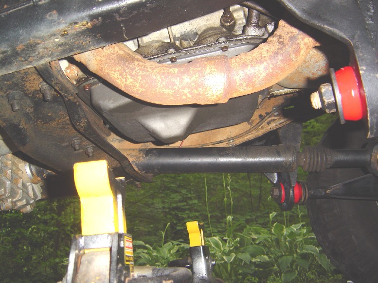 Undercarriage view with rusty exhaust pipe, sway bar with red poly bushings, on yellow jack stands