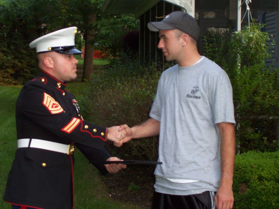 Man in Marine dress uniform shakes hands with civilian