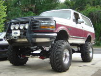 1993 Ford Bronco - This lifted 1993 Ford Bronco features a prominent grille guard with auxiliary lights and large off-road tires.