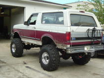 1993 Ford Bronco - Rear view of a modified 1993 Ford Bronco with a two-tone paint job and large off-road tires.
