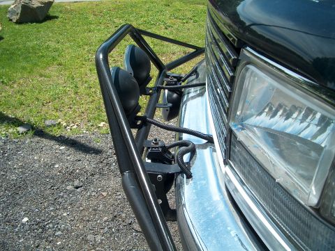 1994 Ford Bronco - The front of a black Ford Bronco is shown with a brush guard and spotlights mounted on the bumper.