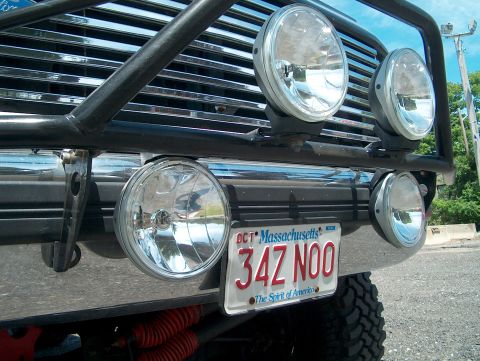 1994 Ford Bronco - Close-up of the front of a vehicle, a chrome grille, a black bull bar, and four auxiliary lights mounted on the bumper.