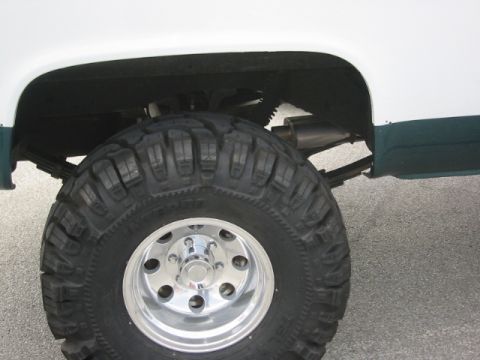 1992 Ford Crown Victoria - Rear wheel and suspension detail of a lifted truck with off-road tires.