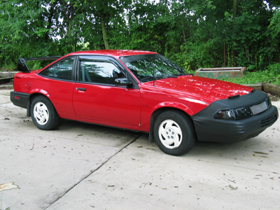 1997 Ford Taurus - A red coupe with a spoiler sits on a concrete surface outdoors.