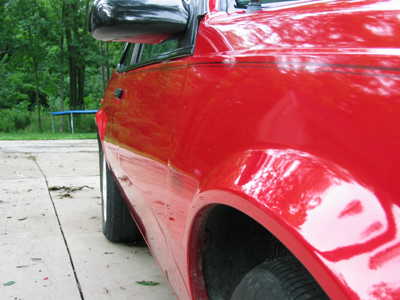 1997 Ford Taurus - Close-up side view of a red car's fender and door, with a watermark at the bottom.