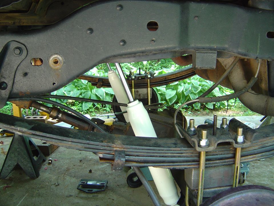 Rear leaf-spring suspension with new white shock and U-bolts, viewed from underneath