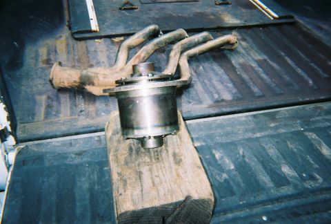 1978 Ford Bronco - Exhaust manifold and catalytic converter resting on a wooden block inside a truck bed.