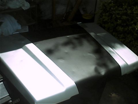 1978 Ford Bronco - The hood of a vehicle, possibly a 1980s model, shows a dent and a black stripe.