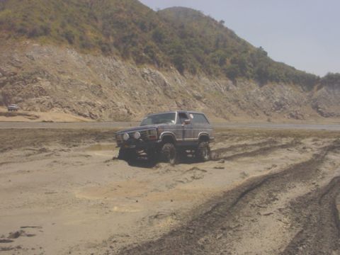 1988 Ford Bronco - This 1988 Ford Bronco appears to be stuck in a muddy, off-road environment.