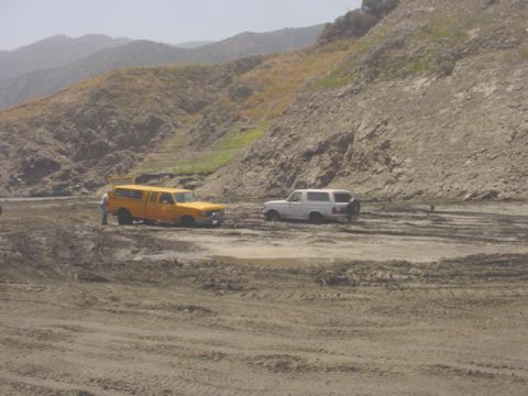 1988 Ford Bronco - Two SUVs are stuck in the mud in a hilly, dry landscape.