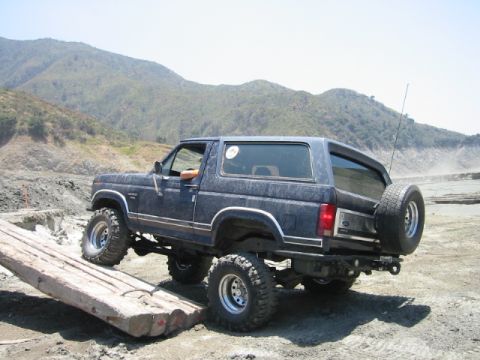 1985 Ford Bronco - This lifted Ford Bronco navigates an obstacle course on a sunny day with dry, mountainous terrain.