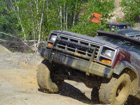 1993 Ford Bronco - This off-road vehicle is navigating a challenging dirt terrain, with another vehicle visible in the background.