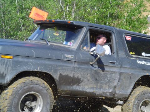 1993 Ford Bronco - A dark gray SUV, possibly a 1978 Ford Bronco, navigates an off-road course with an orange flag attached to its roof visor.