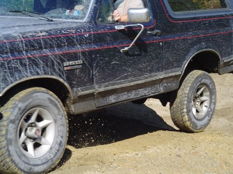 1993 Ford Bronco - Muddy 1993 Ford Bronco navigating an off-road trail.