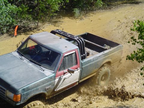1993 Ford Bronco - A modified Ford F-Series pickup truck navigates a muddy off-road course.