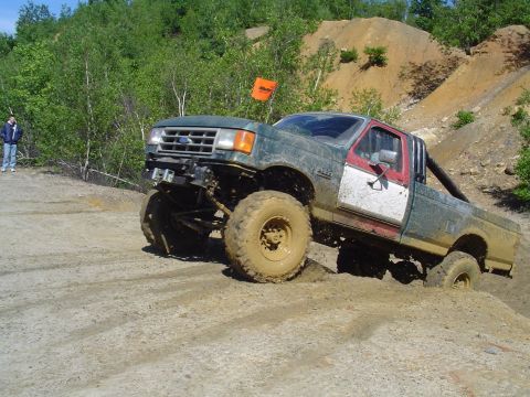 1993 Ford Bronco - This heavily modified Ford pickup truck is navigating a muddy off-road course.