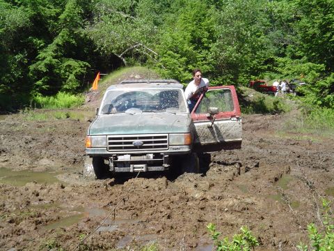 1993 Ford Bronco - This Ford Bronco is deep in the mud, with a person exiting the vehicle.