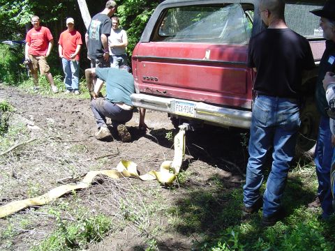 1993 Ford Bronco - Ford Bronco stuck in mud, people trying to pull it out with a strap. License plate FCX-9342.
