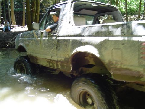 1993 Ford Bronco - This 1993 Ford Bronco is navigating through water and mud in a forest setting.