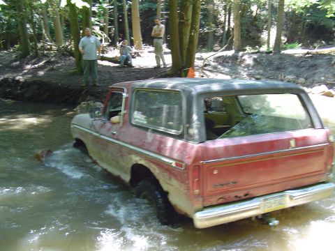 1993 Ford Bronco - This older model Ford Bronco navigates a water obstacle in a forest setting.
