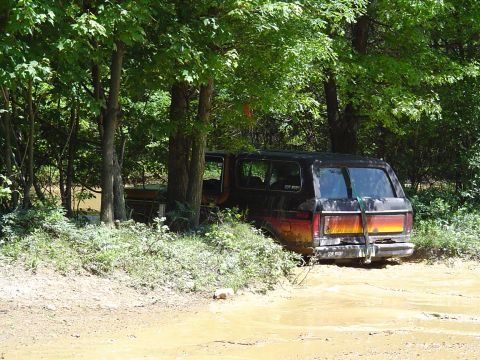 1993 Ford Bronco - This 1993 Ford Bronco is partially submerged in mud, with trees surrounding it.